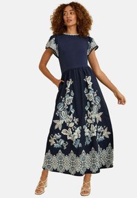 Abito maxi blu navy con maniche corte a palloncino, caratterizzato da ricami floreali in azzurro chiaro e crema, e una silhouette svasata con tasche.