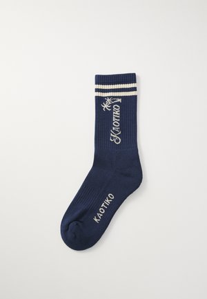 Calzino a coste blu navy con strisce bianche nella parte superiore. Presenta il nome del marchio "KAOTIKO" in ricamo bianco sul lato.