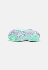 Semelle d’une chaussure translucide vert menthe et violette avec une semelle antidérapante texturée et le logo Crocs sur la zone de la voûte plantaire.