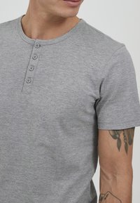 Gray short-sleeve t-shirt with a round neckline and four button placket. The fabric appears knit and soft, with a smooth texture.