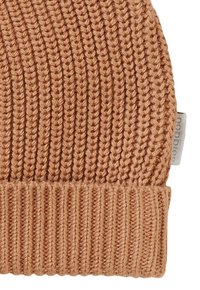 Bonnet en tricot de couleur beige chaud, présentant une texture côtelée avec des motifs verticaux et horizontaux. Étiquette en tissu visible sur le côté.