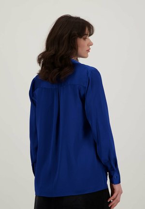 Koninklijkblauw lange mouw shirt met een achterste yoknaad en knoopmanchetten, gemaakt van soepel, lichtgewicht stof. Effen ontwerp zonder patronen.