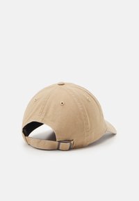 Kaki bomull caps med buet skjerm, justerbar bakstropp og knapp på toppen. Har sydd detaljer og ventilasjonsøyler.