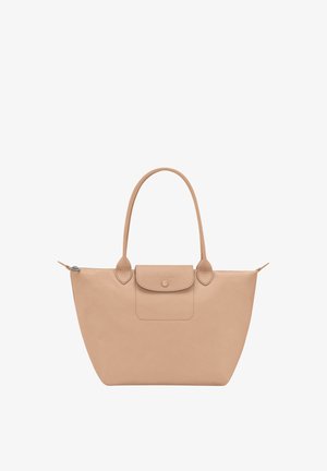 Beige large tote bag with rounded handles, a front flap pocket with button closure, and a zipper on top.
