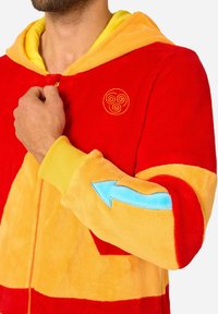 Red and yellow plush hooded onesie featuring an embroidered spiral symbol and a blue arrow detail on the sleeve. Soft texture.