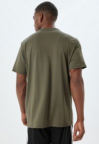 Olijfgroene T-shirt met korte mouwen, gemaakt van zachte stof, met een eenvoudig ontwerp en rechte snit, met een gladde textuur en zonder patronen.