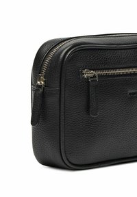 Svart läderväska med en texturerad yta; har en dubbel dragkedja, platt handtag och en elegant design som visar minimalistiska hårdvarudetaljer.