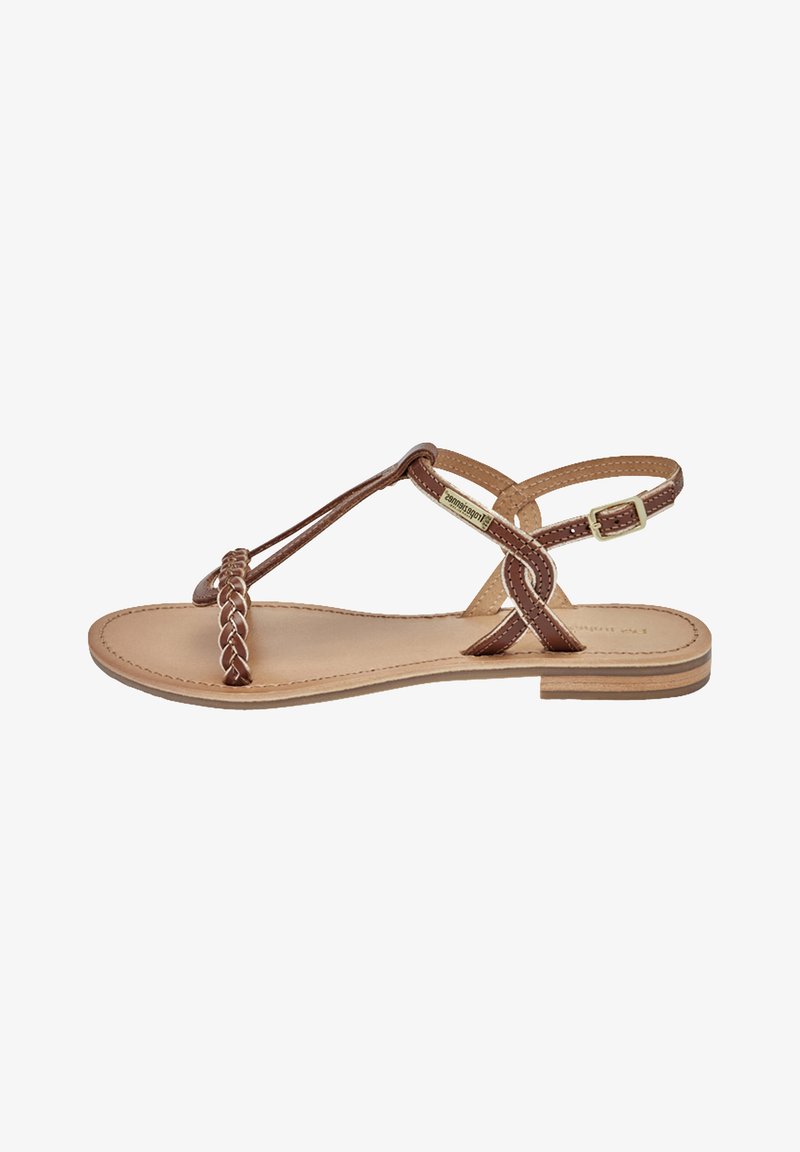 Sandal in pelle marrone con fascetta intrecciata sul dito e design a incrocio alla caviglia. Presenta una suola piatta e chiusura con fibbia regolabile. Stile minimalista.