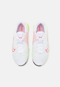 Scarpe sportive bianche con dettagli rosa, logo rosso sul lato e sulla linguetta, lacci bianchi e suole giallo chiaro viste dall'alto.
