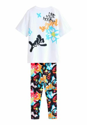 Un t-shirt graphique blanc avec des designs colorés en spray peint et du texte. Un legging noir et multicolore avec des motifs de graffiti audacieux.