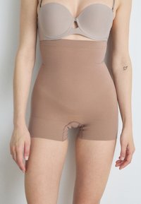 Beige seamless shapewear shorts with high waist, elastic material, and a small gusset opening, designed for comfort and a smooth silhouette.