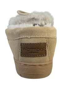 Botín de ante marrón con forro de pelo gris suave, etiqueta rectangular con "Warmbat Australia" y suela de goma texturizada.