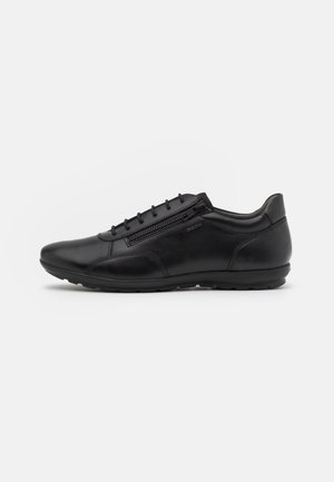 Zapatos de cuero negro con un diseño elegante, que presentan una cremallera lateral y cordones, textura suave y una suela de goma flexible.