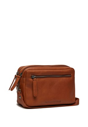 Bruine leren crossbodytas met voorvak met rits en verstelbare band op een witte achtergrond.