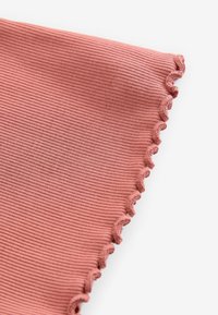 Tissu côtelé de couleur rose poussiéreux avec un détail de bordure ondulée. Texture douce avec une apparence légère.