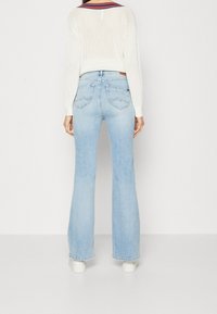 Ljust blå utsvängda jeans med hög midja, bakfickor med en subtil design och ett mjukt, något texturerat denimtyg.