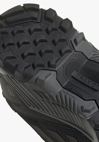 Svart atletisk skosula med ett robust, strukturerat mönster med hexagonala och triangulära former för förbättrat grepp.