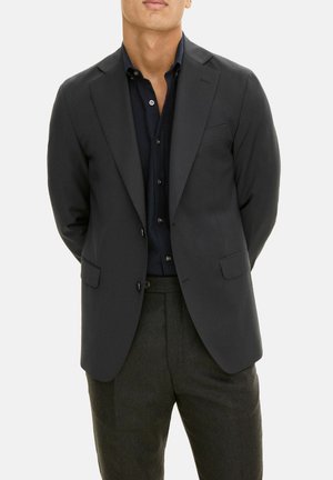 Blazer noir cintré, design à un bouton, revers crantés, deux poches avant, associé à une chemise foncée à boutons et un pantalon cintré.