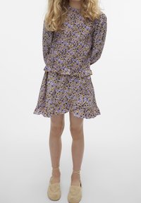 Šaty s květinovým potiskem obsahující fialkové a žluté květy, se stupňovitými volány v pase a na lemu, s dlouhými rukávy a kulatým výstřihem.