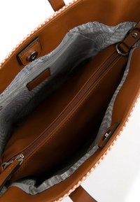 Sac à main synthétique marron avec un intérieur à motif, comprenant une poche centrale zippée, une fermeture à bouton-pression magnétique et une bordure rayée contrastante.