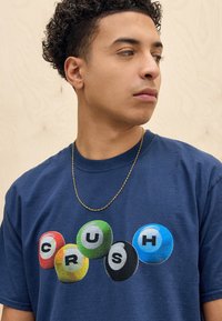 Navy blue cotton t-shirt featuring multicolored billiard ball graphics with the word "CRUSH" in the center. Simple round neck design.
