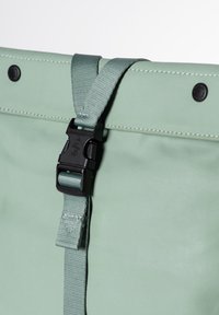 Borsa verde menta con superficie texturizzata. Presenta una fibbia in plastica nera e cuciture lungo i bordi. Finitura liscia con angoli arrotondati.