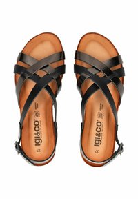 Černé kožené sandály s křížovými pásky, otevřenou špičkou a nastavitelné kotníkové popruhy. Hnědá kožená stélka s embosovaným logem.