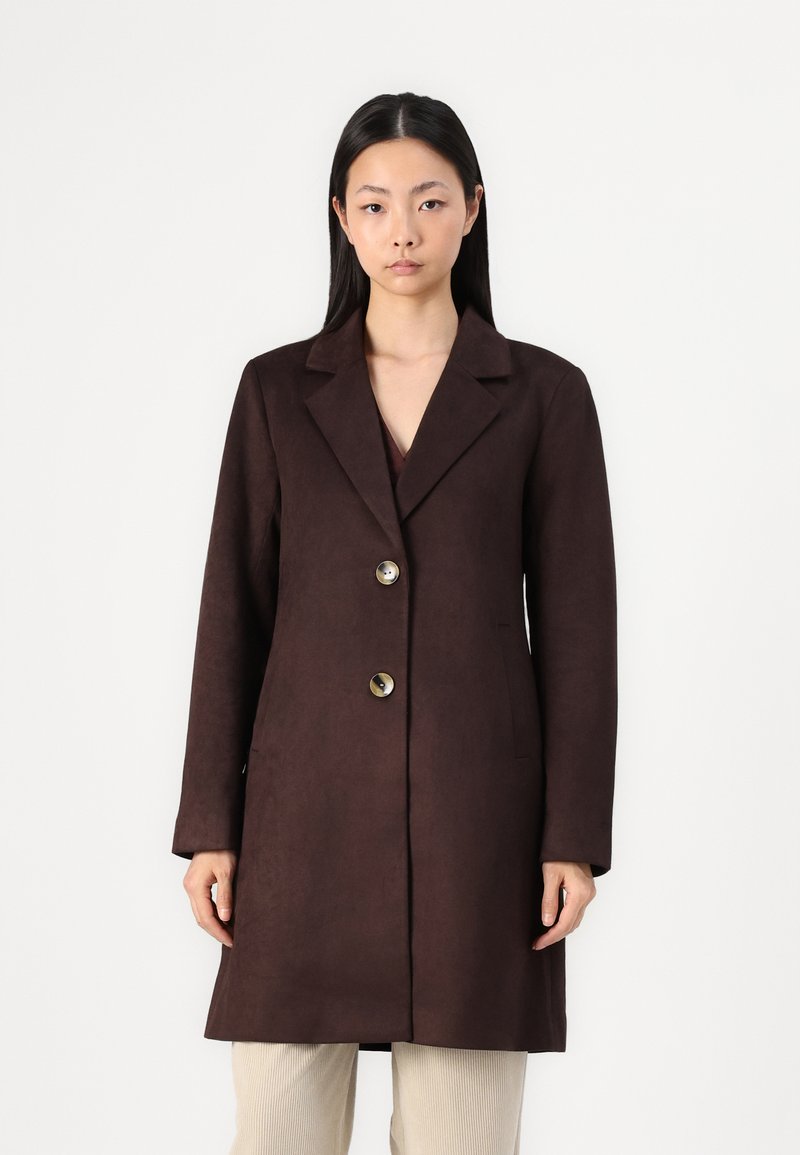 Manteau marron en suède avec un col cranté et trois boutons proéminents. Il possède des manches longues et une coupe décontractée avec des poches latérales.