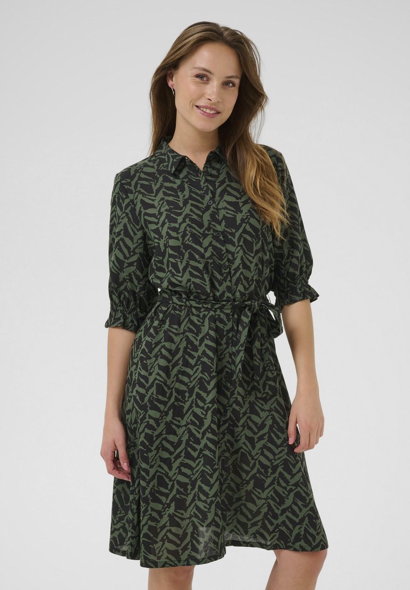 Robe verte à motif avec un devant à boutons, des manches courtes bouffantes et une ceinture à nouer, fabriquée en tissu léger avec un design fluide.