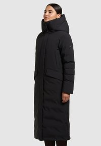 Lang sort dunjakke med høj krave, der har to forlommer og et elegant, quiltet design for isolering og varme.