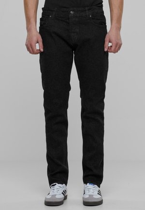 Černé džíny z denimu se slim fit střihem, obsahující pět kapes, poutka na opasek a zapínání na knoflík. Textura vypadá mírně zoxidovaně.