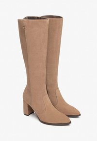 Kniehoge beige neplederen laarzen hebben een spitse neus, een blokhak en een zijrits, met een gladde textuur en naadloos ontwerp.