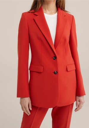 Blazer rojo con un diseño a medida, dos bolsillos frontales y dos botones negros, fabricado en una tela suave con un ajuste estructurado.