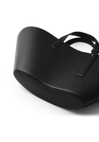 Sort læder tote bag med en buet form, der har to stropper og minimal hardware. Glat tekstur med polerede syninger.