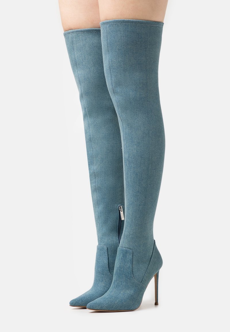 Lårhöga denimstövlar i ljusblått med en åtsittande design, spetsig tå och stilettklack; har en sidoglash för enkel påtagning.