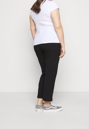 T-shirt blanche ajustée, à manches courtes, associée à un pantalon slim noir et des baskets grises. Design simple avec une texture lisse.