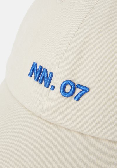 Beige caps laget av teksturert stoff med blå brodert tekst "NN. 07" på forsiden. Buet skjerm og strukturert design.