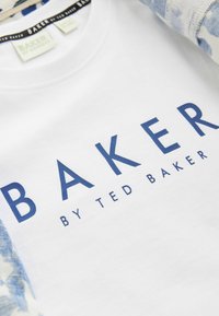 Camisa de algodón blanca con el texto azul "BAKER BY TED BAKER", con mangas largas en un patrón abstracto azul claro. Cuello redondo.