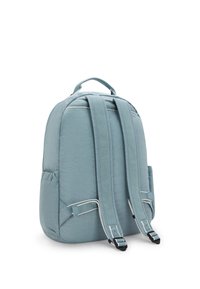 Mochila de color azul claro con correas acolchadas, tela texturizada, forma redondeada y un asa en la parte superior. Bolsillos laterales y detalle de costura en contraste.