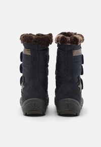 Navy winter boots with a suede bottom, puffy textile upper, and faux fur collar, featuring multiple adjustable straps on the side.