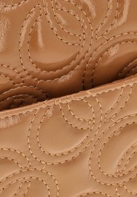 Beige læder pung med en glat overflade, detaljeret syet spiral mønster og synlige sømme langs kanterne.