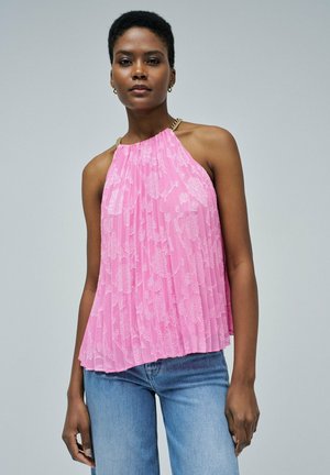 Top de tirante halter rosa con diseño plisado y patrón floral, featuring un cuello de cadena en tono dorado y un corte holgado. Combinado con jeans de denim claro.