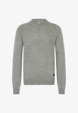 Vienkāršs pelēks džemperis, kas izgatavots no mīkstas adītas auduma. Tam ir apaļa kakla izgriezums, garas piedurknes un ribotās aproces un apakšmalas. Smalka tekstūra.