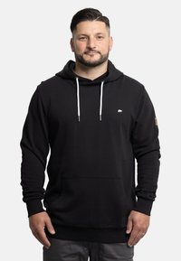 Black hoodie made of soft fabric, featuring a kangaroo pocket, white drawstrings, and a small logo on the chest. Accented with a leather tag.