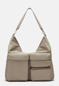 Sac à épaule en cuir beige avec une texture lisse, comportant deux poches avant, une sangle ajustable et une fermeture éclair.