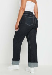 Högmidjade, mörkblå jeans i denim med uppvikt fåll, vit sömnad och två bakfickor. Styla med vita sneakers.