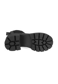 Semelle de botte en caoutchouc noir avec des rainures profondes, dotée d'un design de semelle à motifs pour une traction et une stabilité accrues. Zones de talon et d'orteil renforcées.