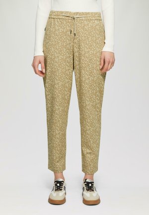 Beige geblokte broek met een elastische tailleband en trekkoorddetail. Zachte stof, smal toelopende pasvorm en zijzakken. Gecombineerd met sneakers.