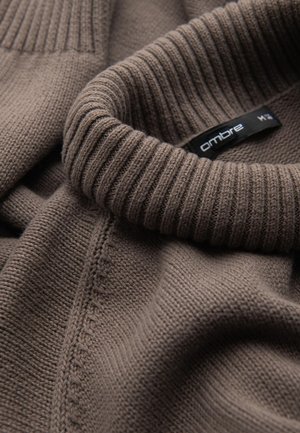 Bruine gebreide trui met een hoge geribbelde kraag, met een gladde textuur en een subtiele glans. Het label zegt "ombre."