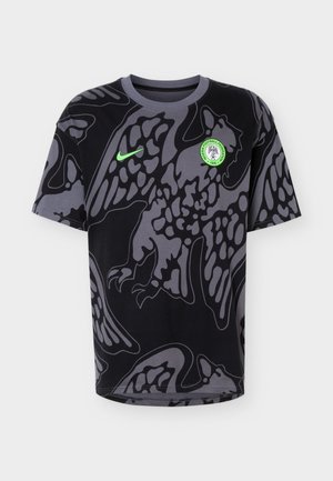 Μαύρο και γκρι κοντομάνικο πουκάμισο με μεγάλο αφηρημένο σχέδιο γερακιού, νέον πράσινο λογότυπο Nike και έμβλημα της Ποδοσφαιρικής Ομοσπονδίας της Νιγηρίας στο στήθος.